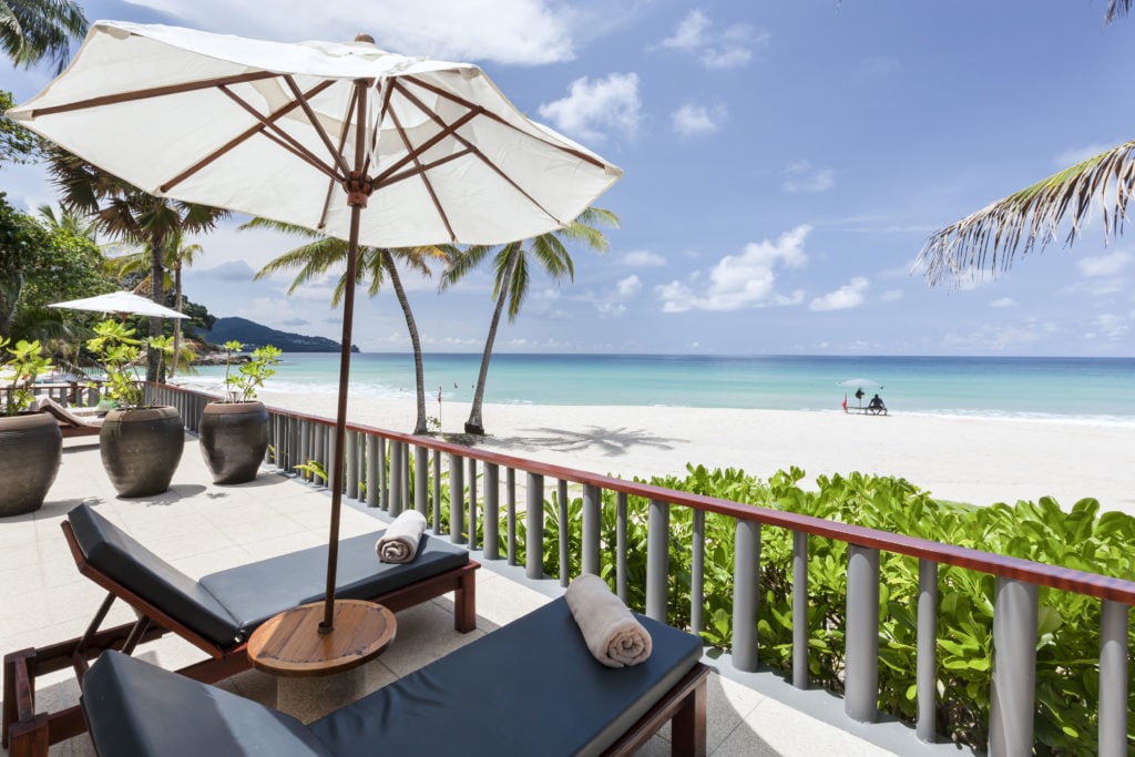 Two beach beds on a hotel patio facing the gorgeous white sand beach
