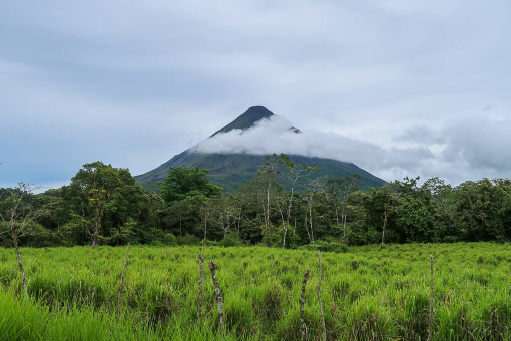 Arenal Volcano surrounded with lush jungle trees and grasslands