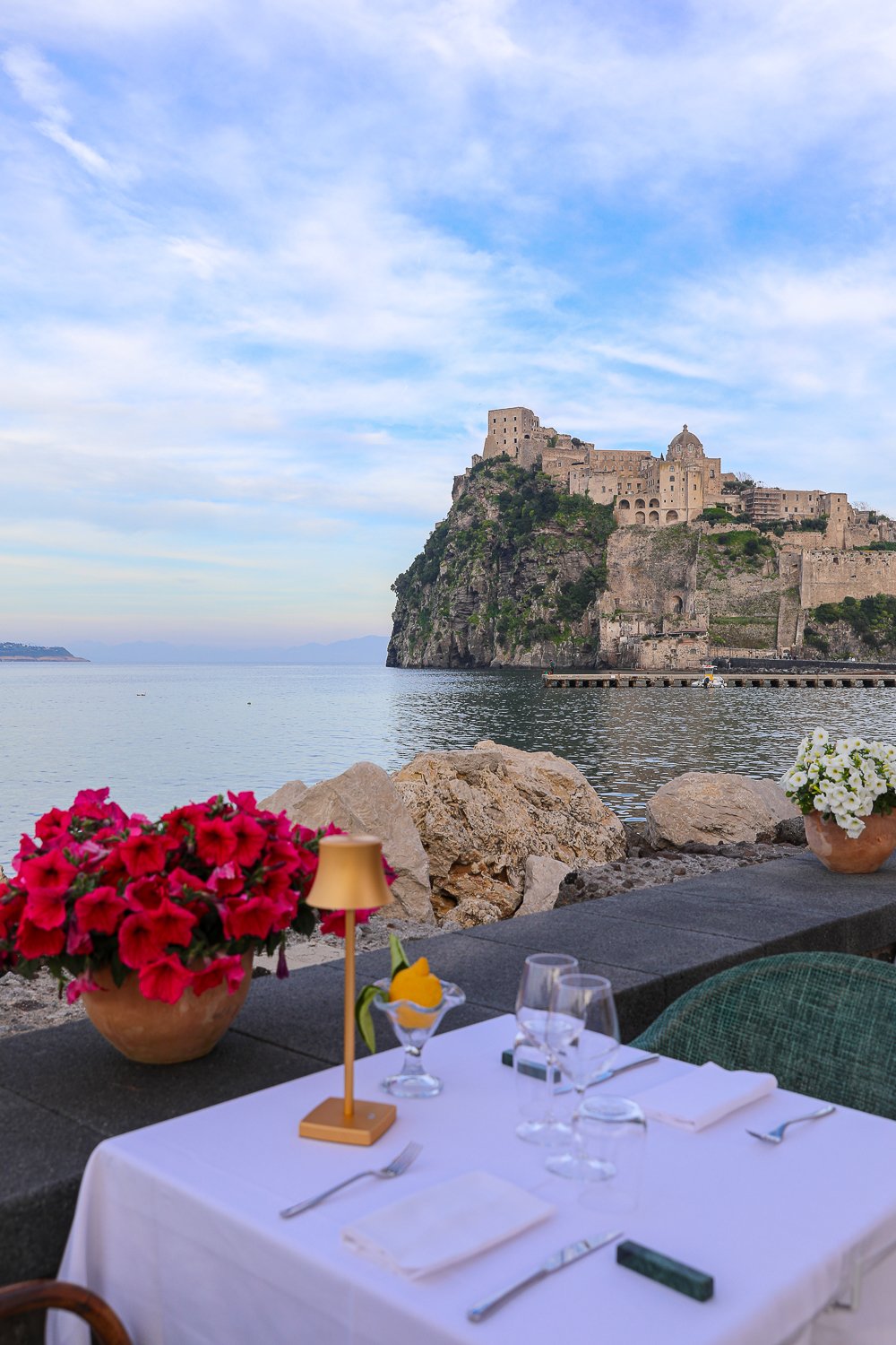 Romantic vibe at Auras restaurant with a view of the sea and Aragonese castle. Dining at this sea-view restaurant is one of the best things to in Ischia, Italy.