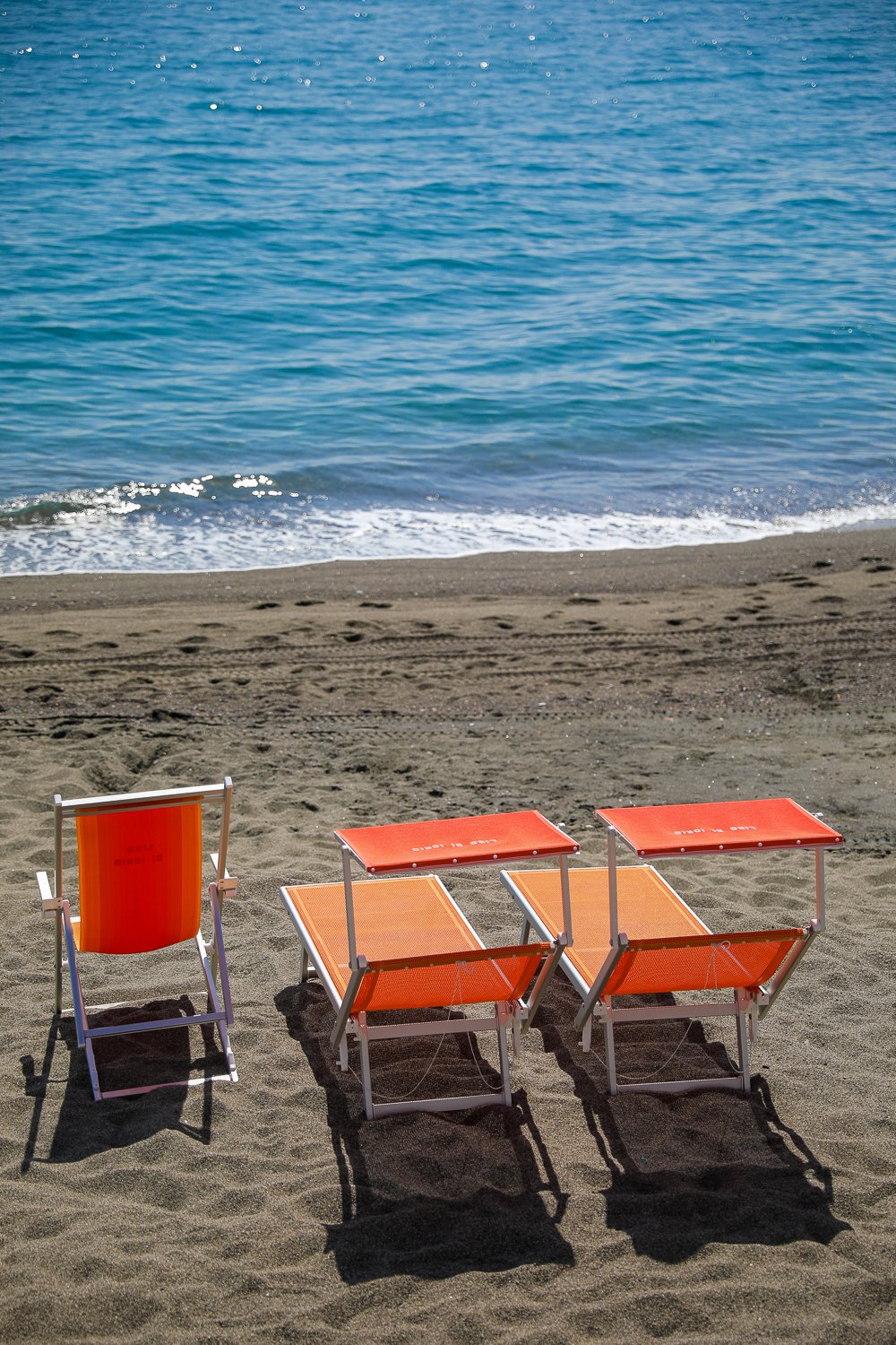 Orange chairs on the beach. Relaxing at beach clubs is one of the best ways to spend a long weekend on Ischia, Italy.