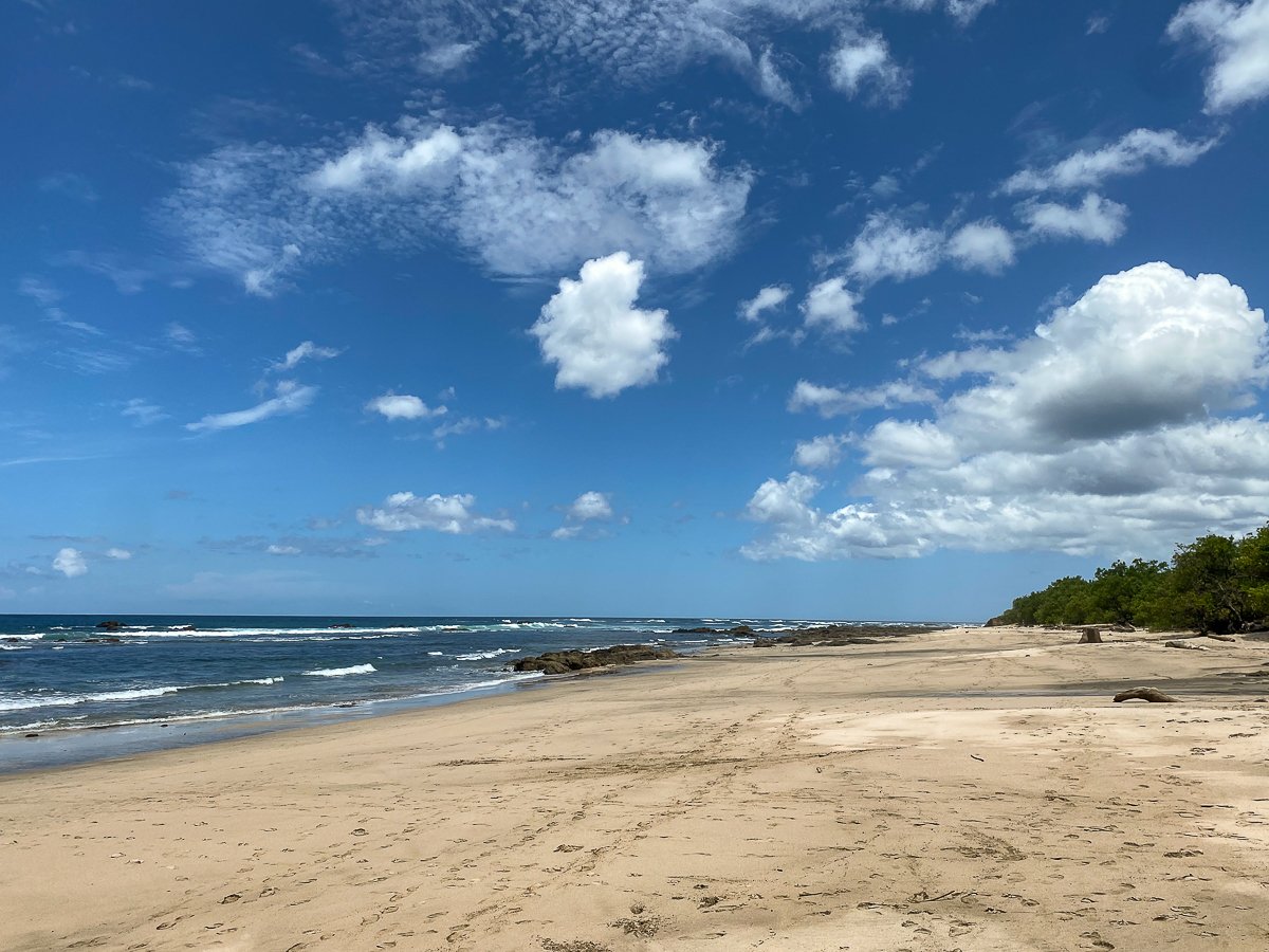 Quiet beach at Playa Avellanas under partly-cloudy skies