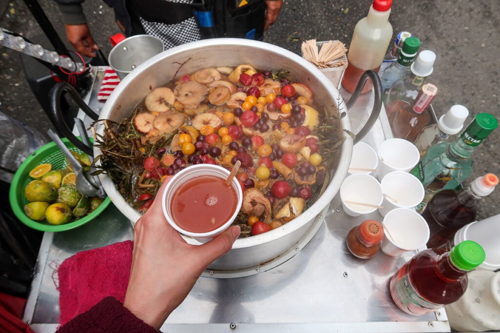 Holding a cup of fruit juice sold in a street. Trying out La Candelaria's street food stalls is one of the top things to do in Bogota, Colombia.