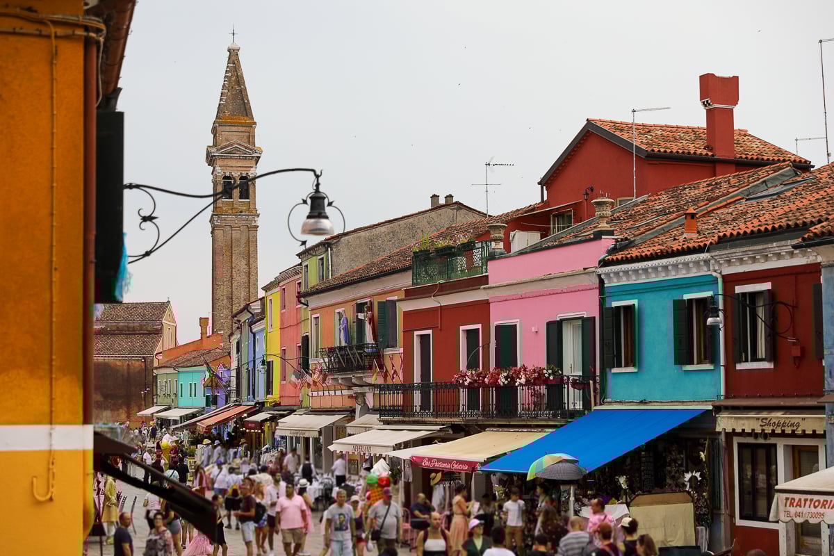 Crowd of tourists walking along the busy, colorful streets of Burano. If you're unsure of what to do in these islands, this guide helps you how to day trip to Murano and Burano.