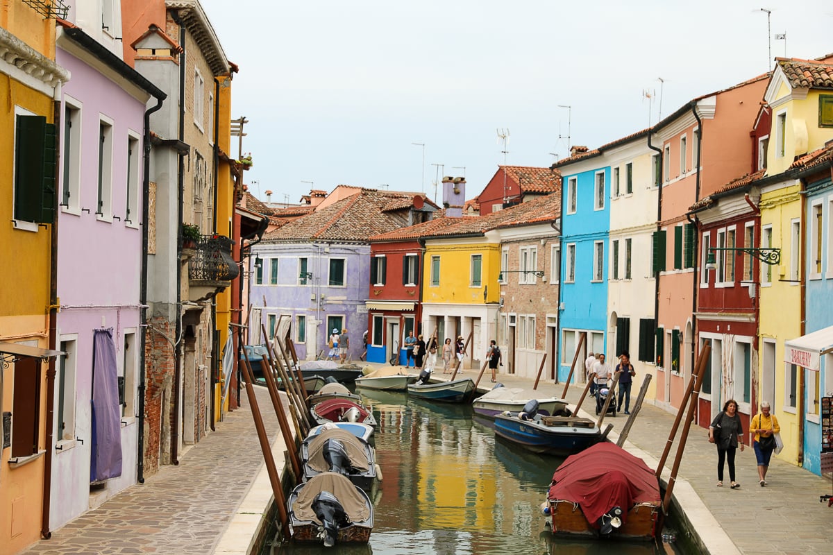Curved canal lined with colorful houses and boats in Burano, Venice