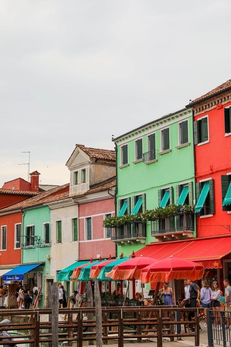 A flock of tourists roaming around the colorful restaurants of Burano, Venice