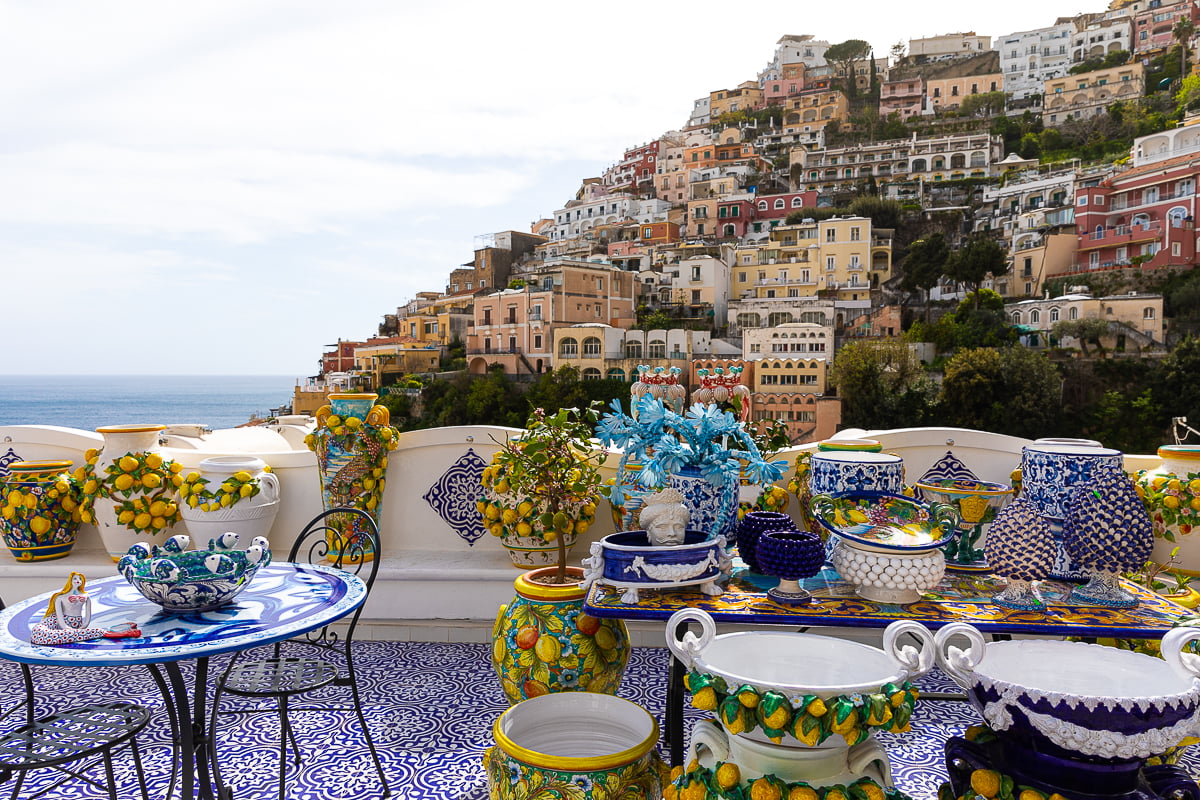 Colorful ceramics displayed on a terrace overlooking a village in Positano. Enjoying this view is one of the many things to do in Amalfi Coast.