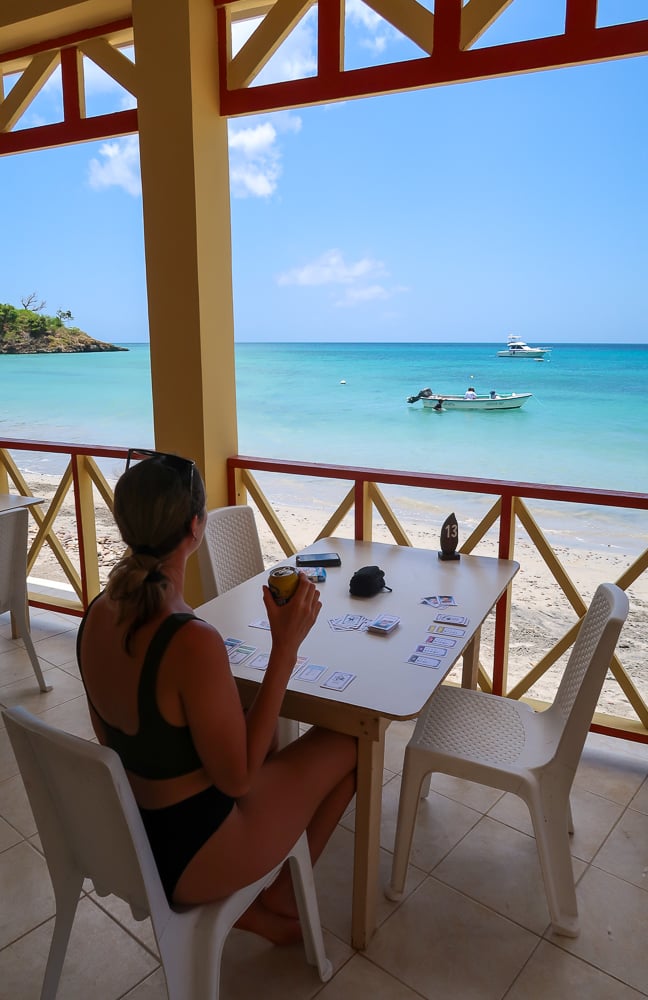Maddy drinking beer from a patio while admiring the view of the beautiful beach