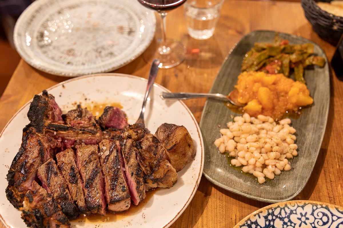 A traditionally prepared 1.4-kg Florentine steak and vegetable side dishes at Ristorante del Fagioli - a must-add to your 3 days in Florence itinerary!