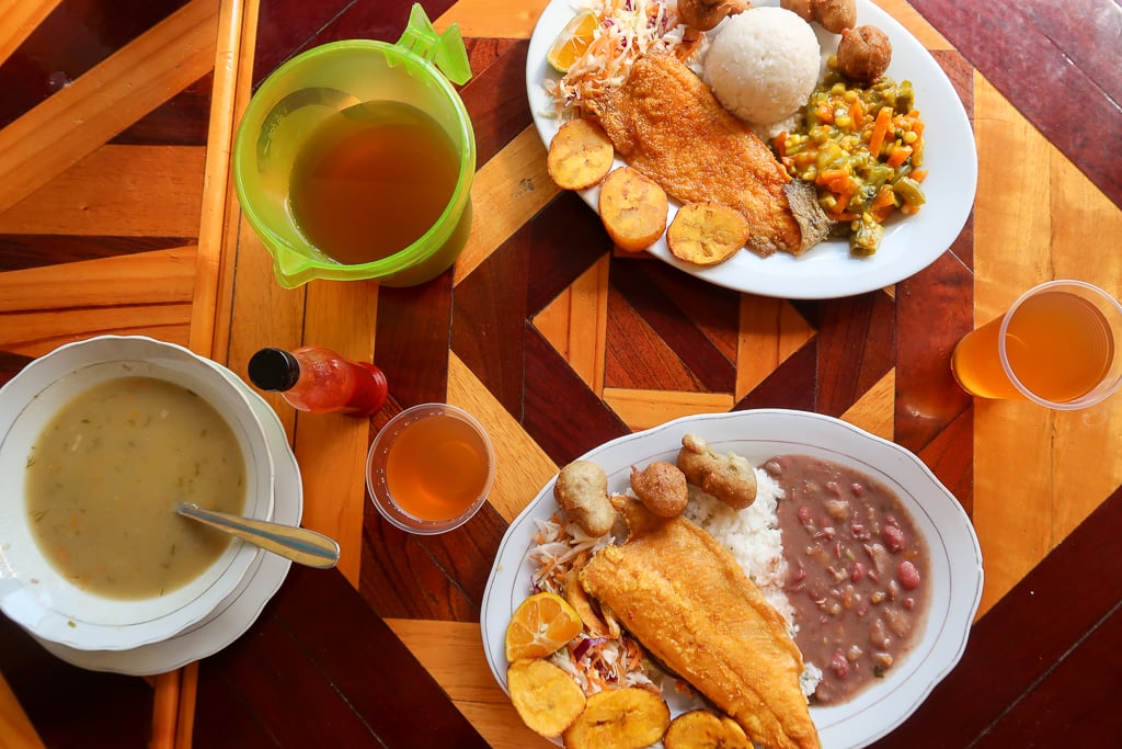 Two delicious trout dishes on white ceramic plates with a pitcher and cups of drink on a wooden table. If you're wondering what to eat in Salento, locals would likely recommend their signature trout dishes.