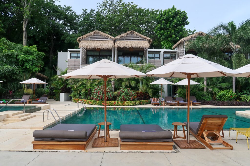 Lounge chairs and beds by the pool at Gilded Iguana Surf Hotel