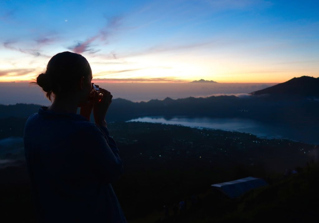 Maddy waiting for sunrise while sipping a hot cup of tea after hiking Bali's Mount Batur at sunrise