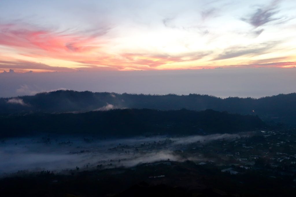 Fogs slowly disappearing as the sun slowly rises up behind the mountains