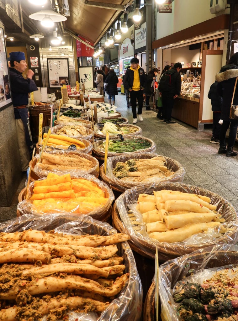 People wandering around Nishiki Market. In this considered Kyoto's Kitchen, you'll find a variety of local dishes and vegetables that you must try during your two days in Kyoto.