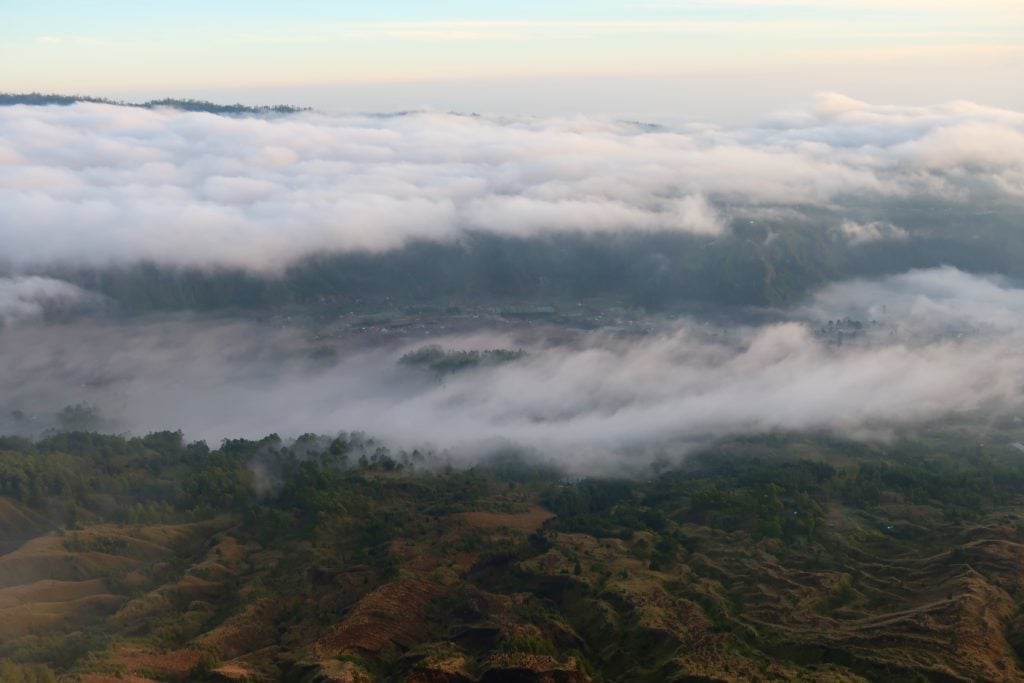 Thick, white clouds above the forests as seen from above while hiking Bali's Mount Batur at sunrise