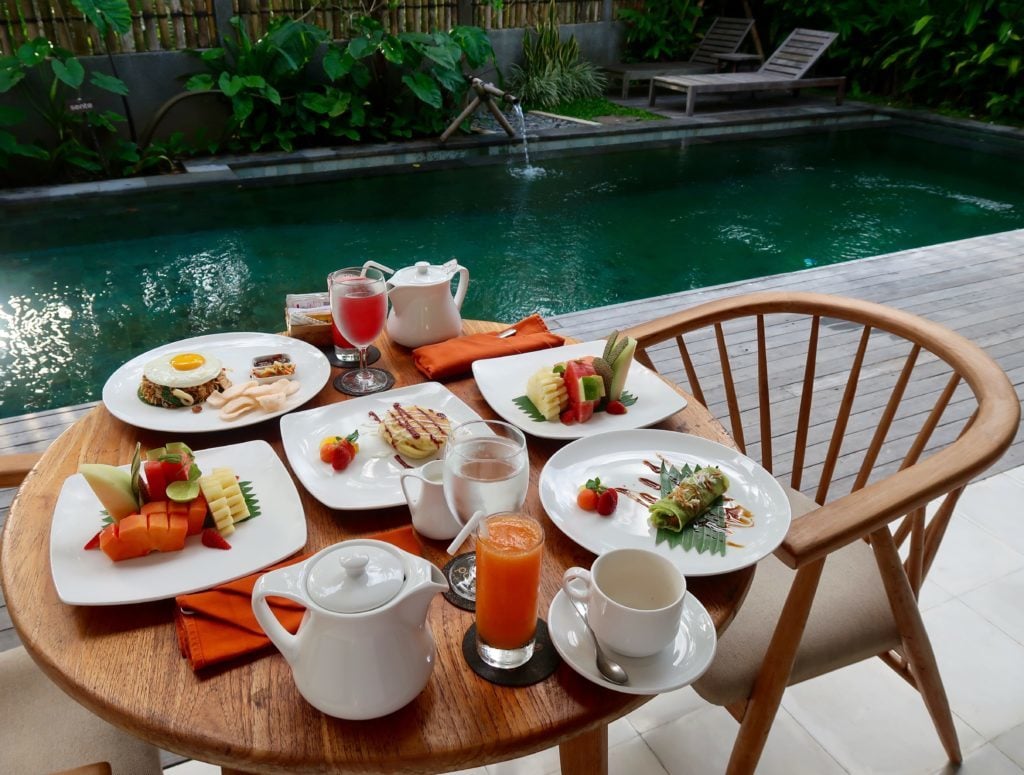 Scrumptious breakfast table filled with Indonesian dishes, fresh fruits and juices