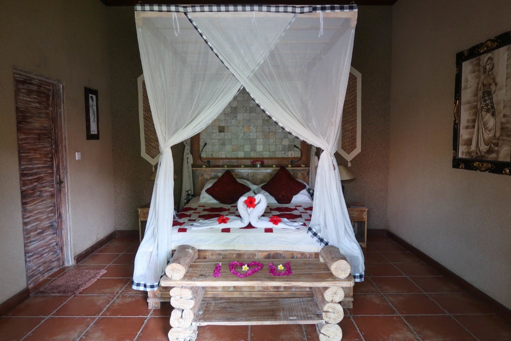 Bed with white canopy, swan towel art and floral displays