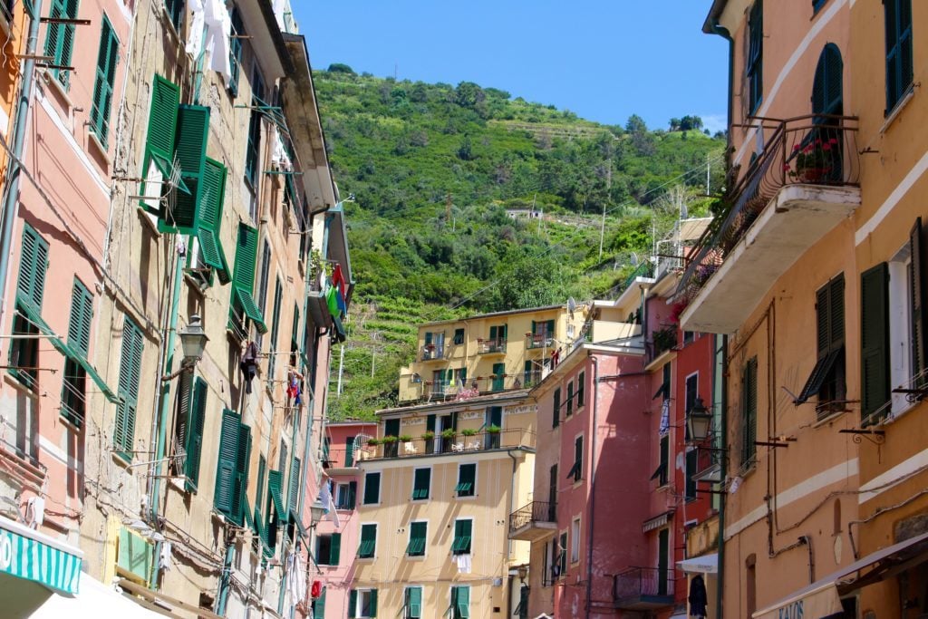 Tall, colorful houses by the foot of a mountain in Vernazza. The town of Vernazza is one of the villages you will visit when you go hiking in Cinque Terre.