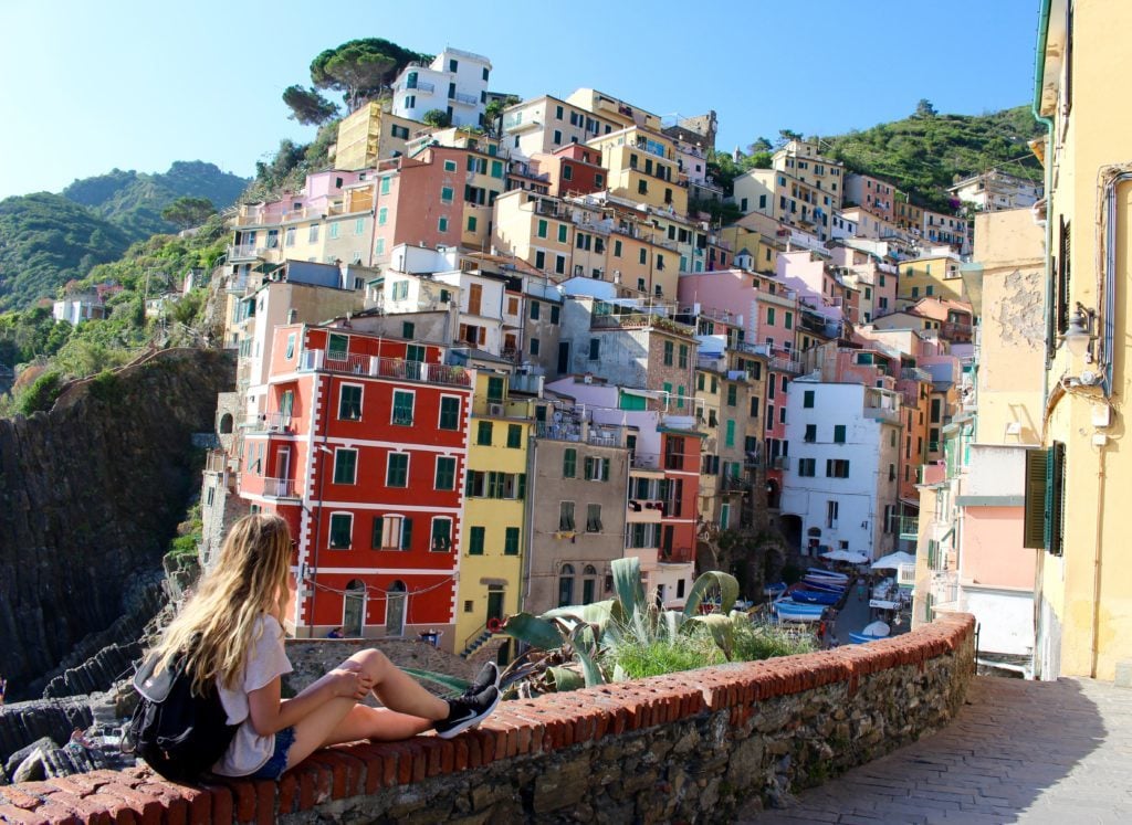 Maddy sitting on a stone fence along the walkway in Riomaggiore.