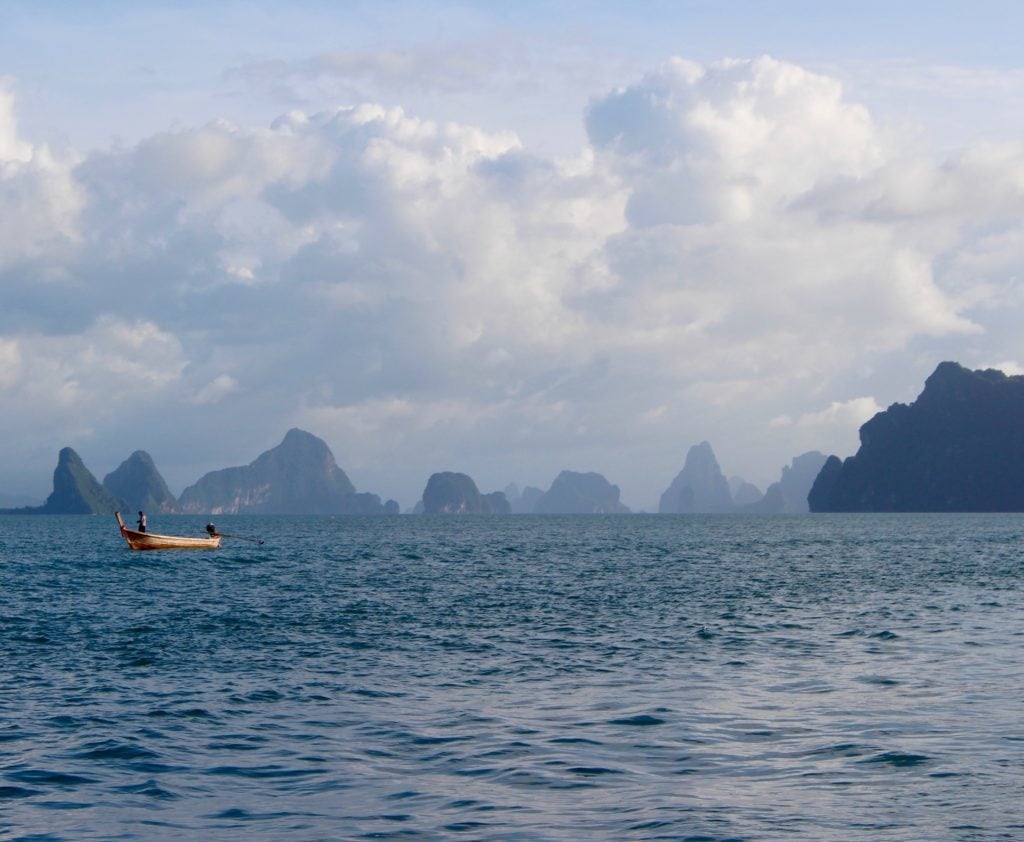 A small boat roaming around the wide ocean while island hopping in Thailand