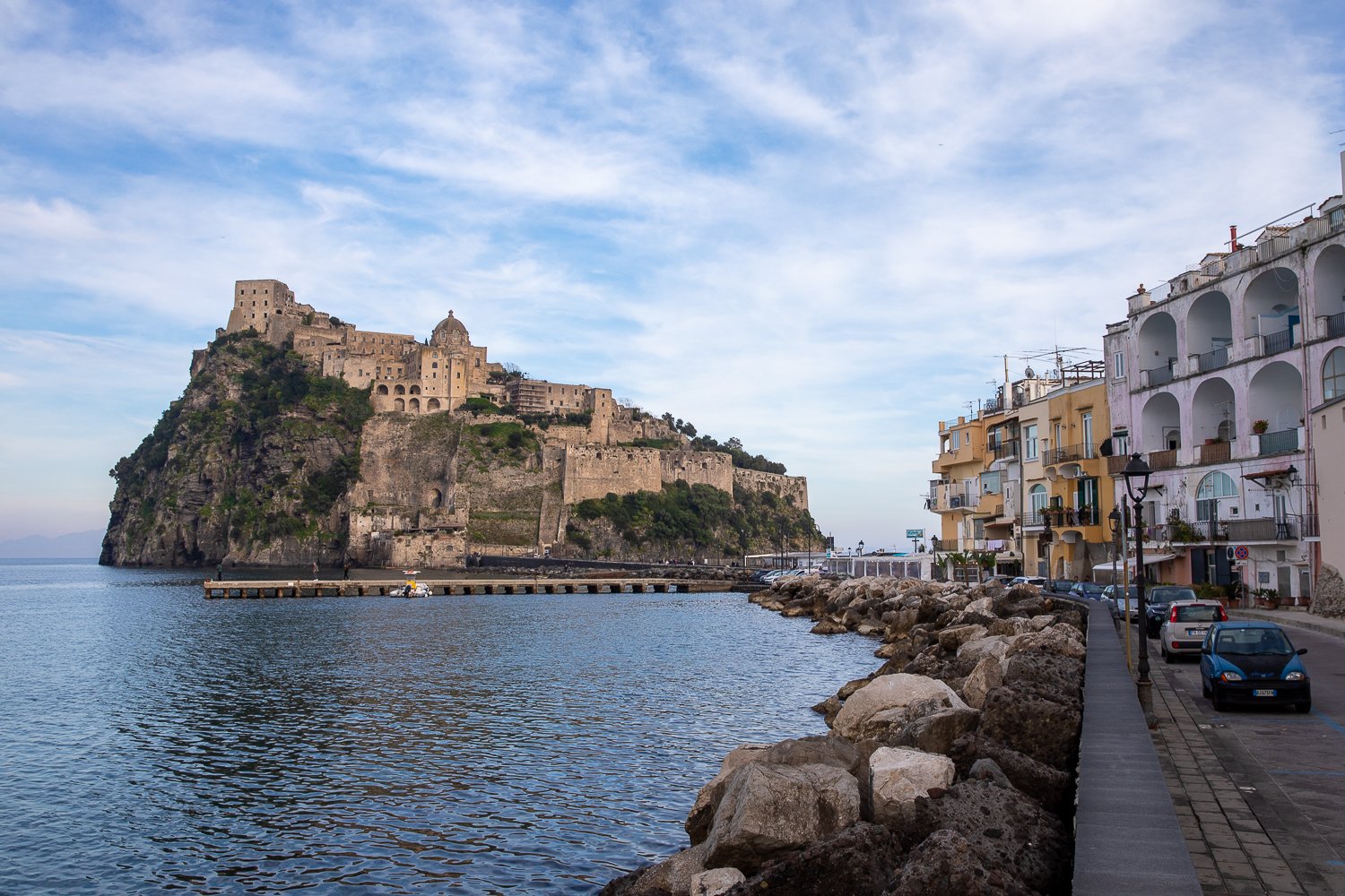 View of Aragonese Castle from the beachside road of Ischia, Italy