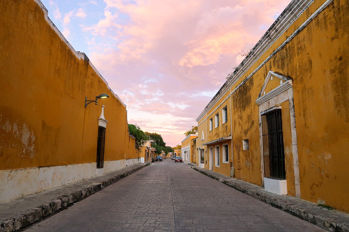 Quaint, quiet street lined with yellow buildings in Izamal, Mexico. In this guide, you'll find the best things to do in Izamal.