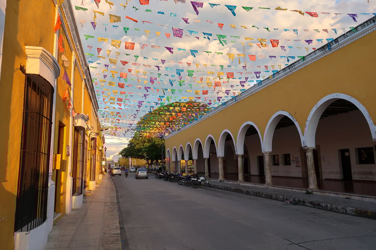 Colorful flags connecting yellow buildings in Izamal