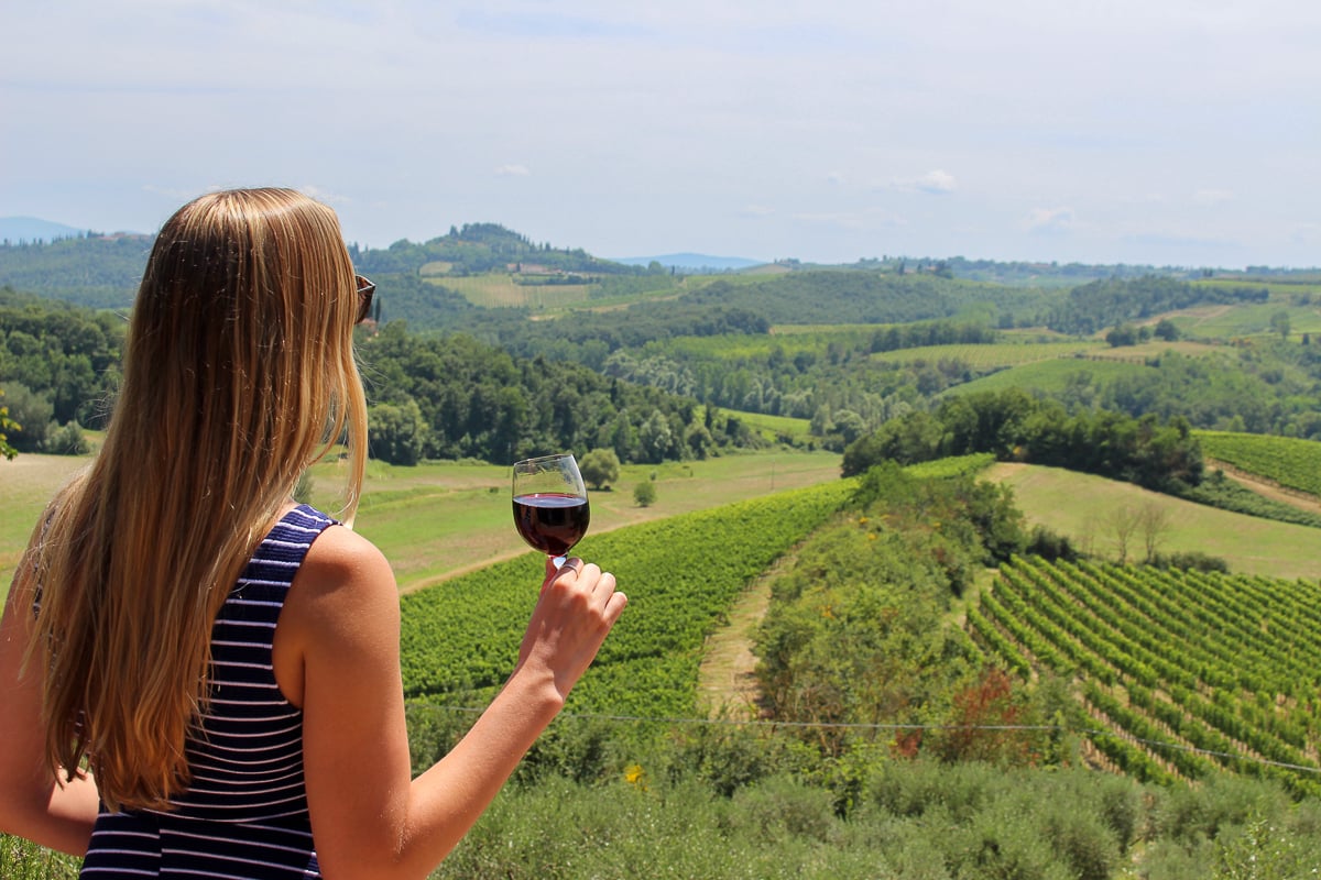 Maddy indulging in red wine while enjoying the panoramic view of Tuscany's vineyards during a delightful day trip from Florence