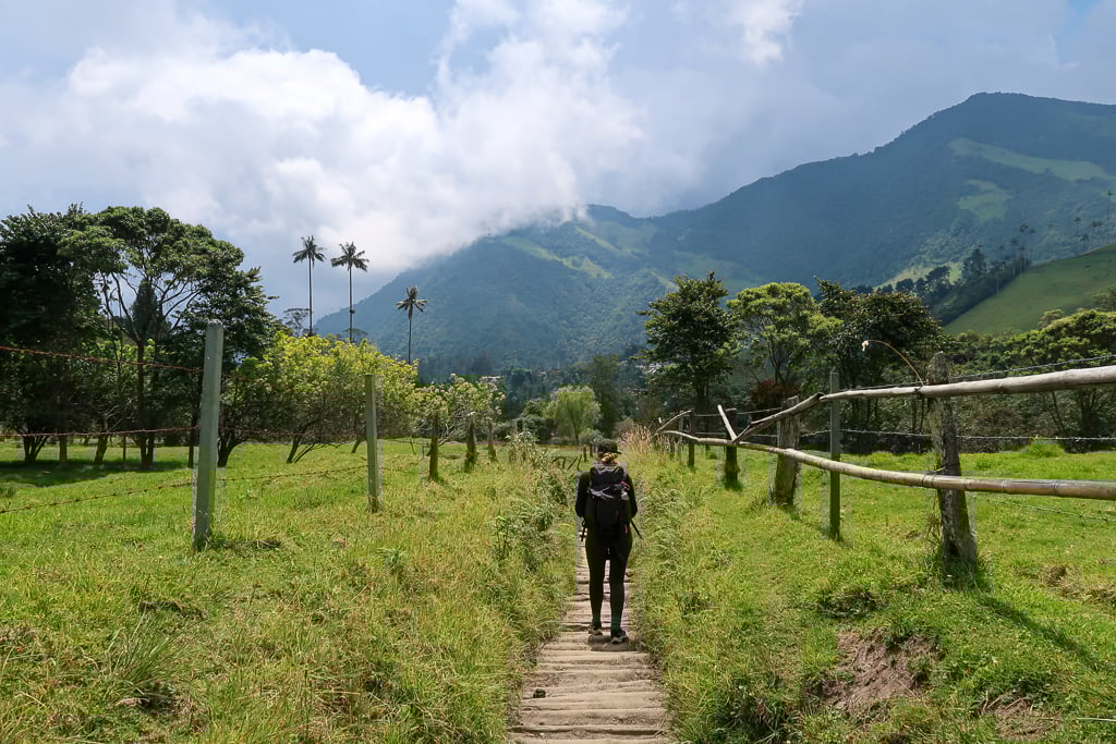 Maddy standing in the middle of a dirt path as she hikes the Cocora Valley on a sunny day.