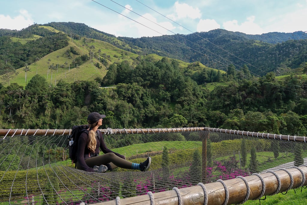 Maddy sitting on an outdoor cargo net hammock while admiring the nature's beauty during daytime