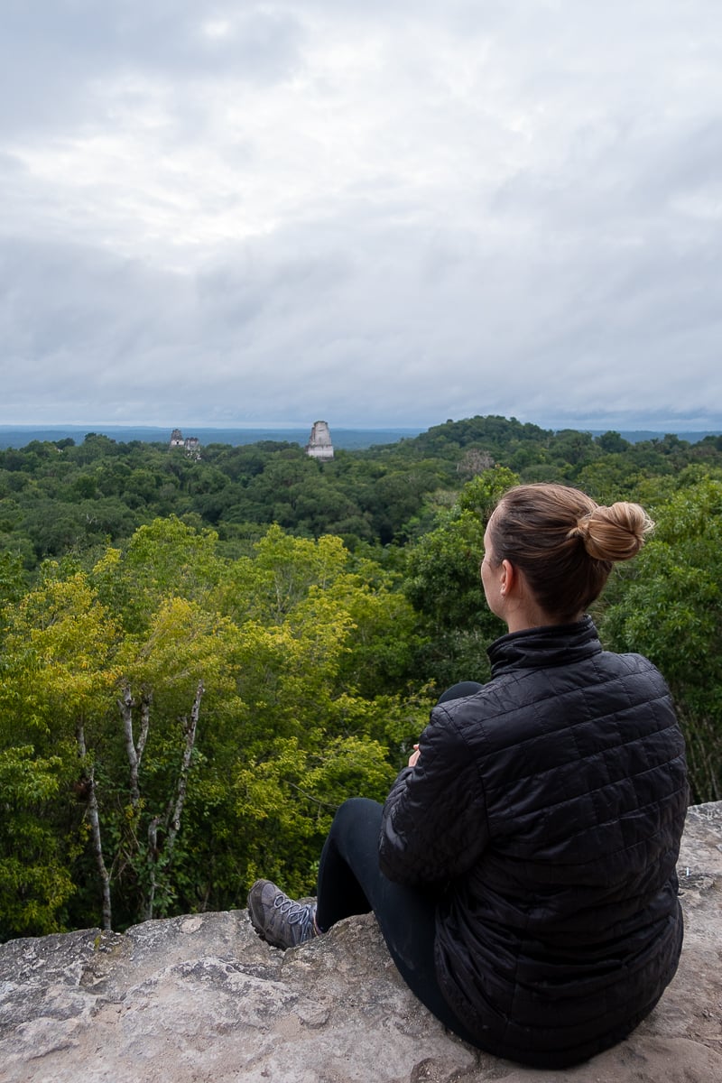 Maddy overlooking the top of Tikal ruins surrounded by lush jungle trees