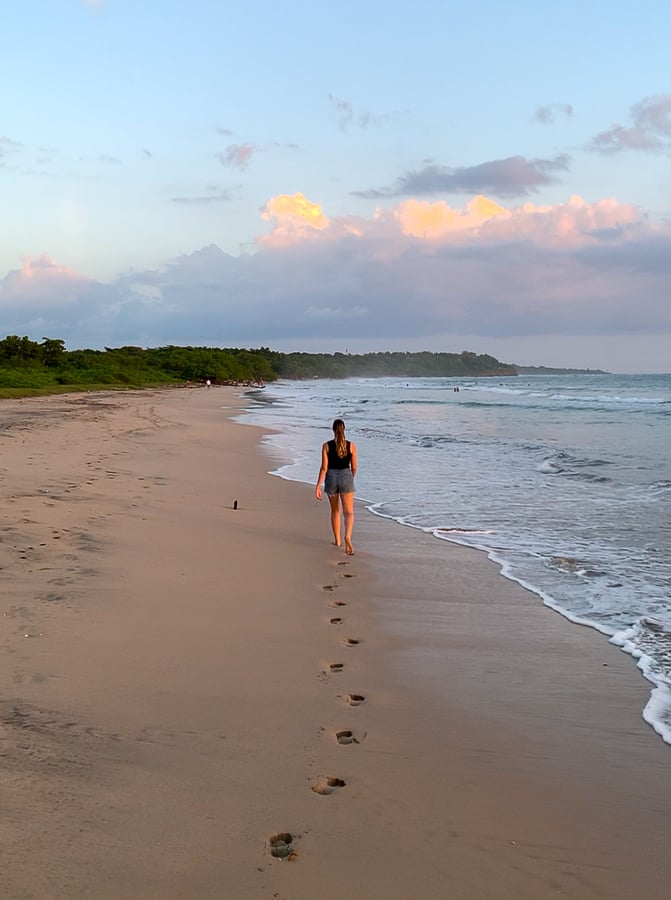Maddy walking along Playa Avellanas while leaving footprints on the sand