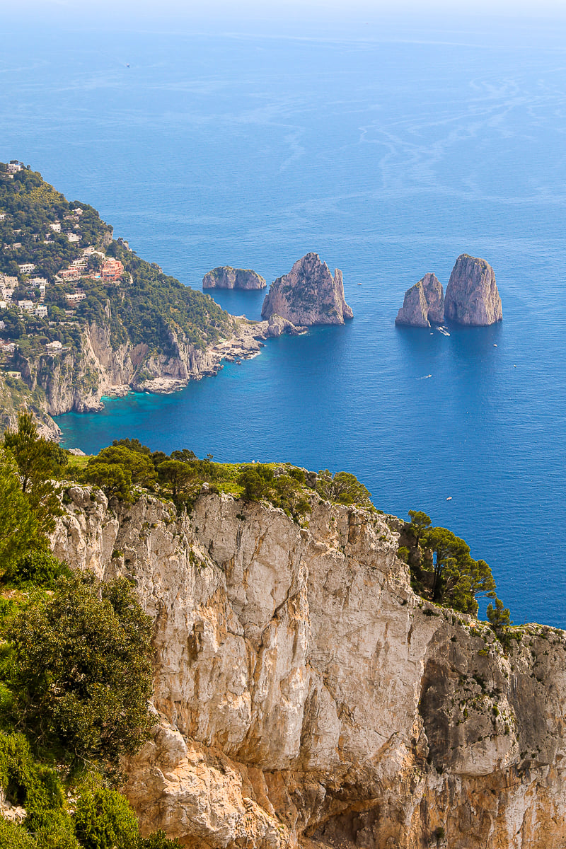 Lush mountains and beautiful rock formations surrounded by blue ocean waters as seen from Monte Solaro, Capri