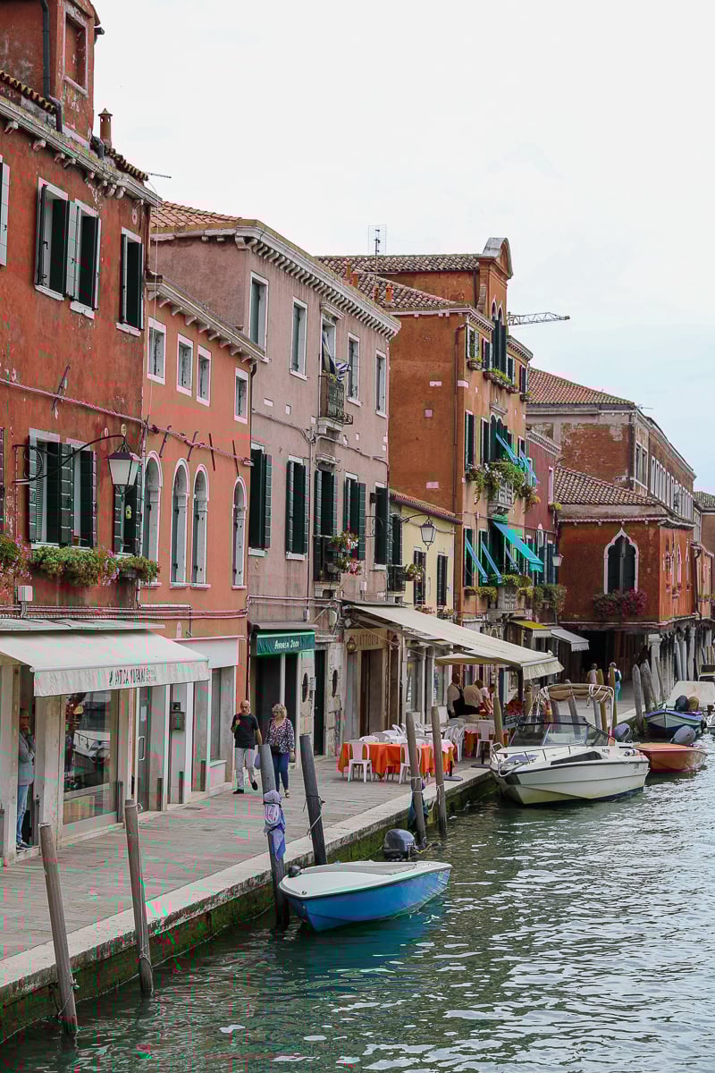 Quaint buildings by a canal with boats docked nearby in Murano, Venice