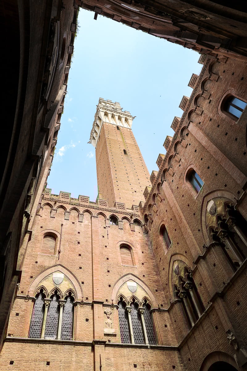 Medieval-style exterior of Torre del Mangia, a must-see clock tower in Siena on your Tuscany In One Day sightseeing tour