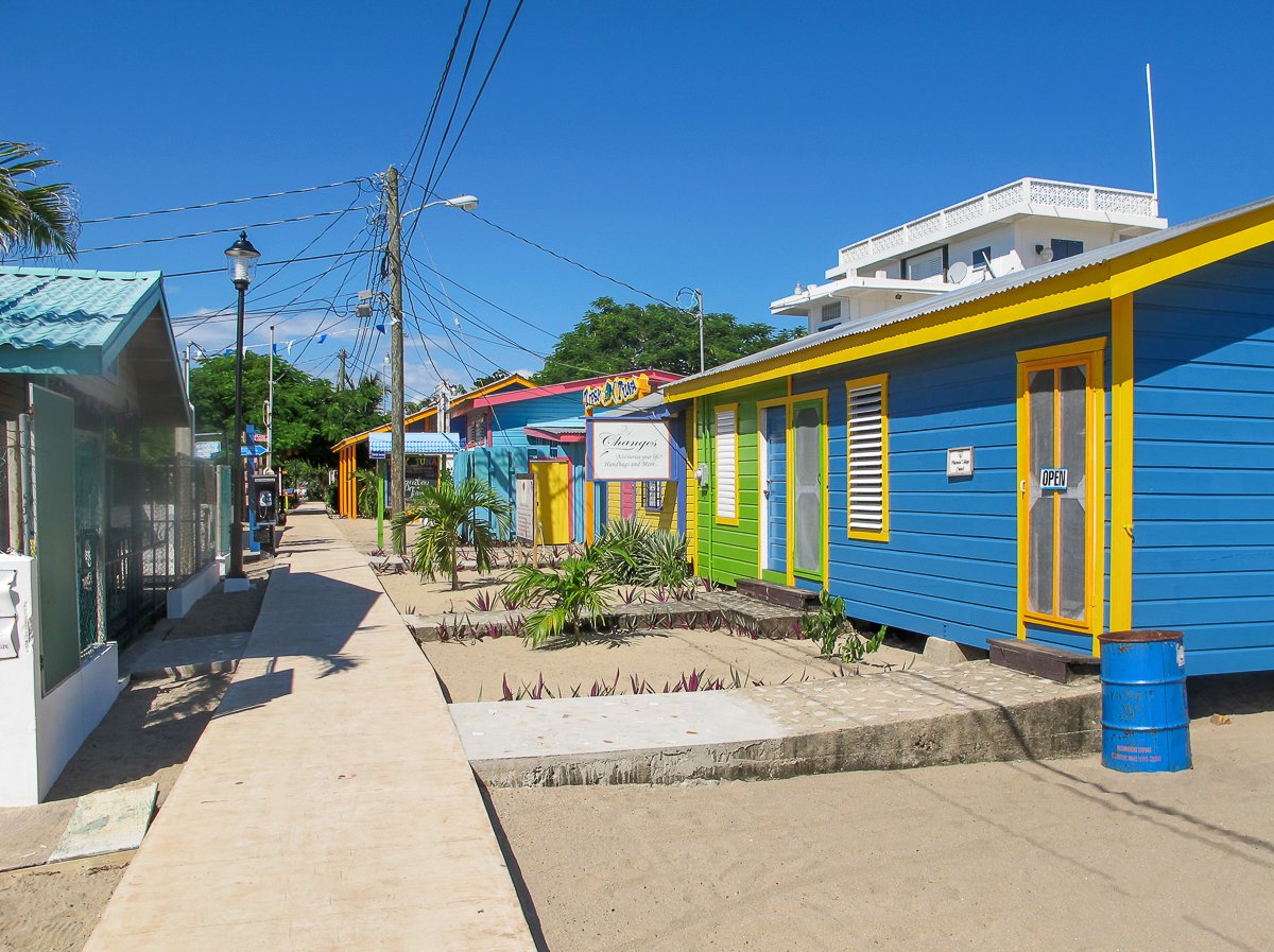 Colorful wooden houses on a sandy street in the town of Placencia in Belize - visiting here is one of the best things to do in Belize.