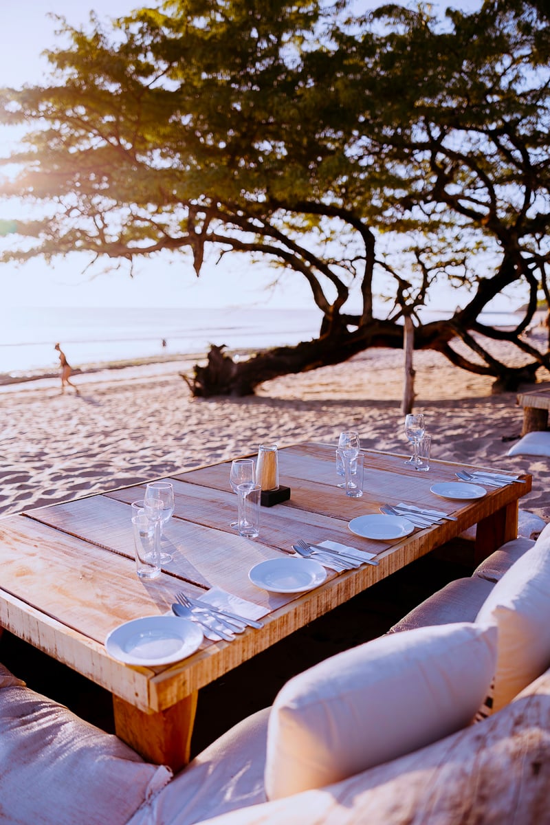 Small wooden table by the beach with empty plates and wine glasses in Popoyo