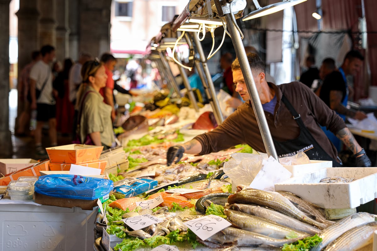 Staff and patrons at the Rialto fish market in Venice - stopping by here is a must on your 2 days in Venice itinerary