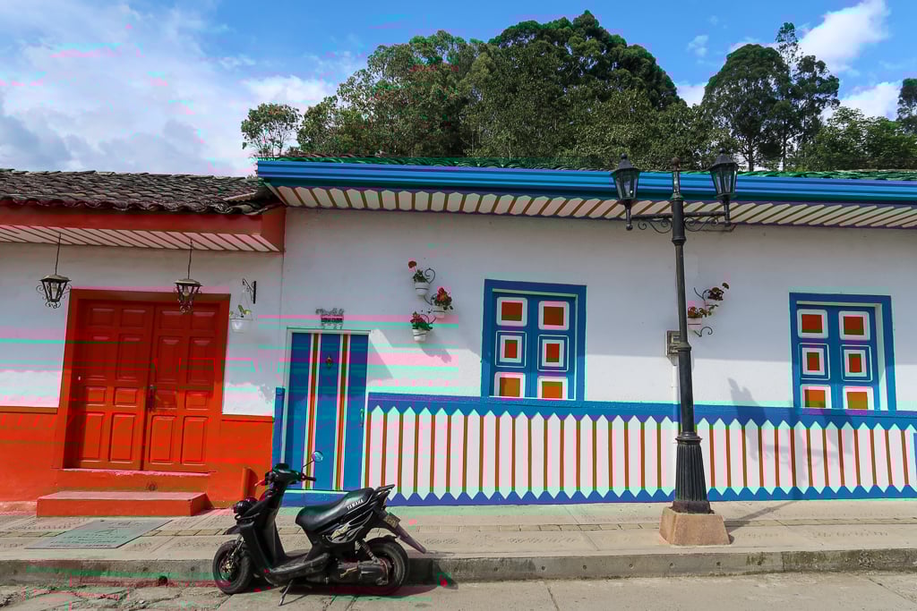 A black motorcycle parked beside a colorful street in Salento, Colombia