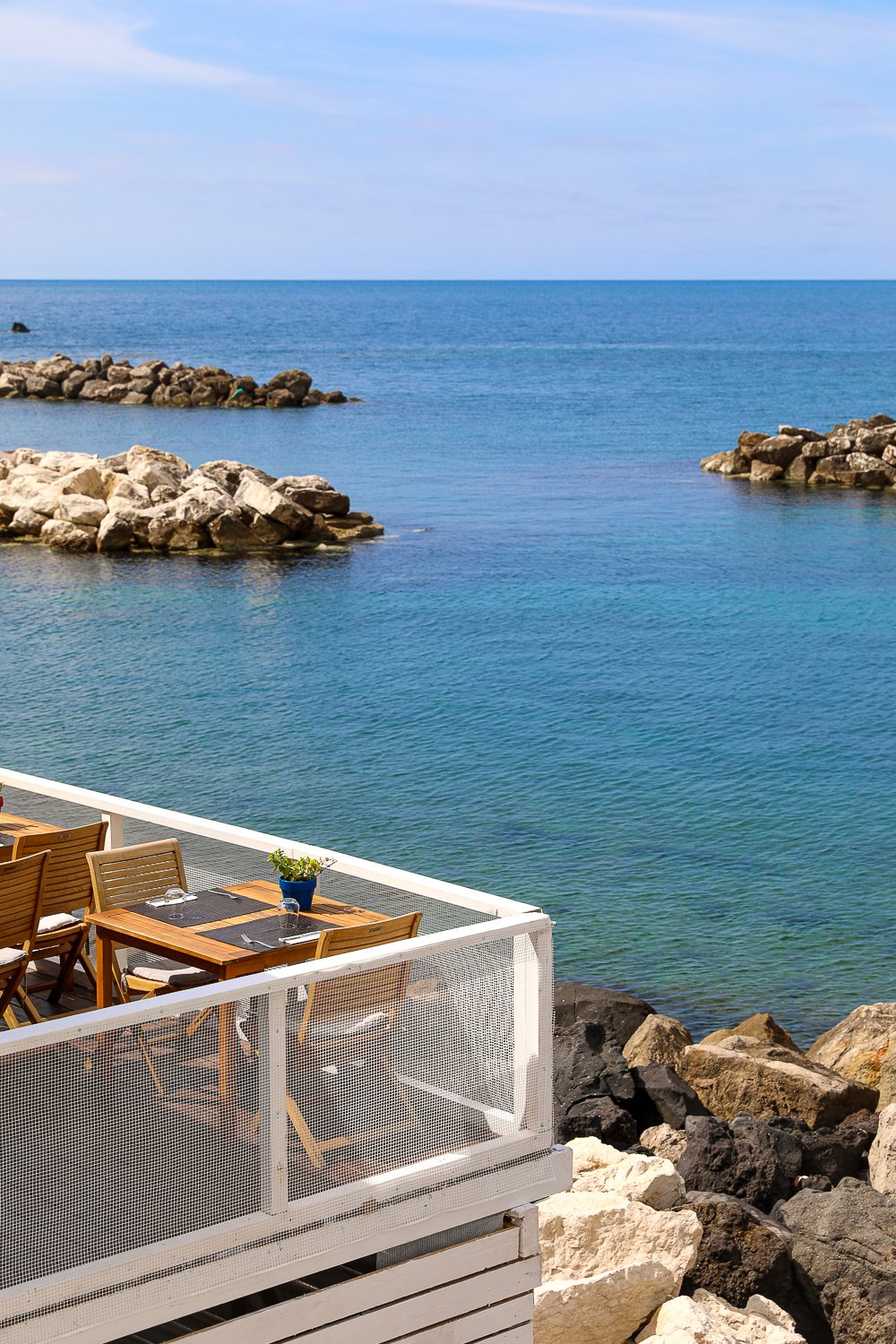 Dining tables and chairs on a terrace overlooking the beautiful beach in Sant'Angelo