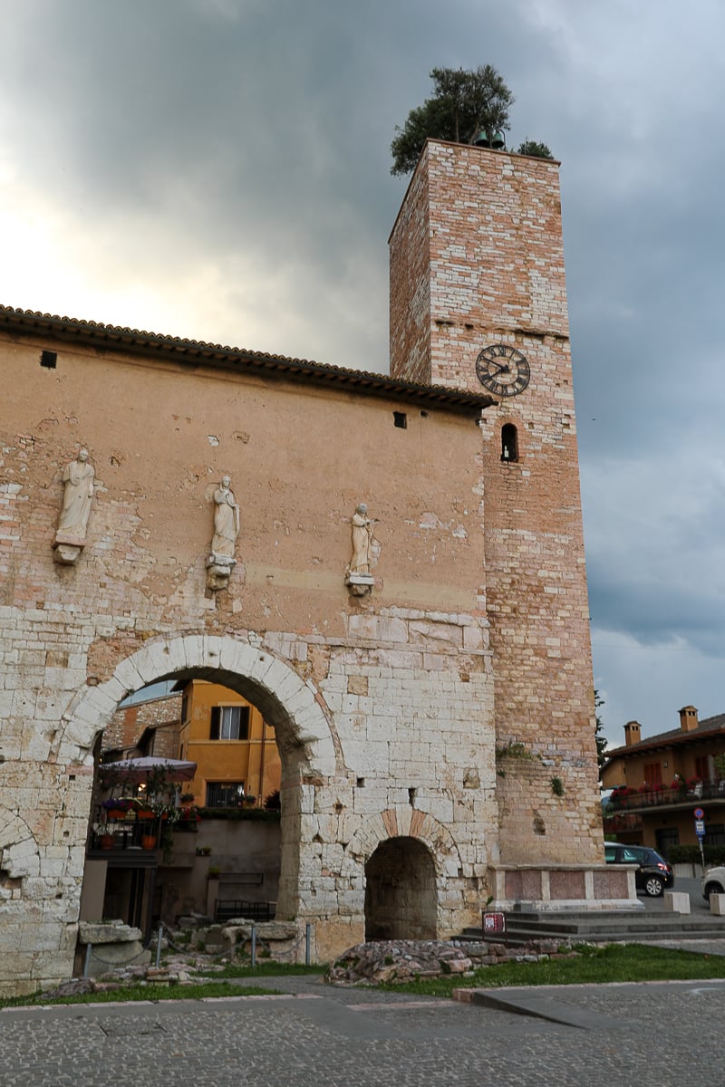 Clock tower with trees and bells on the roof in Spello, Italy