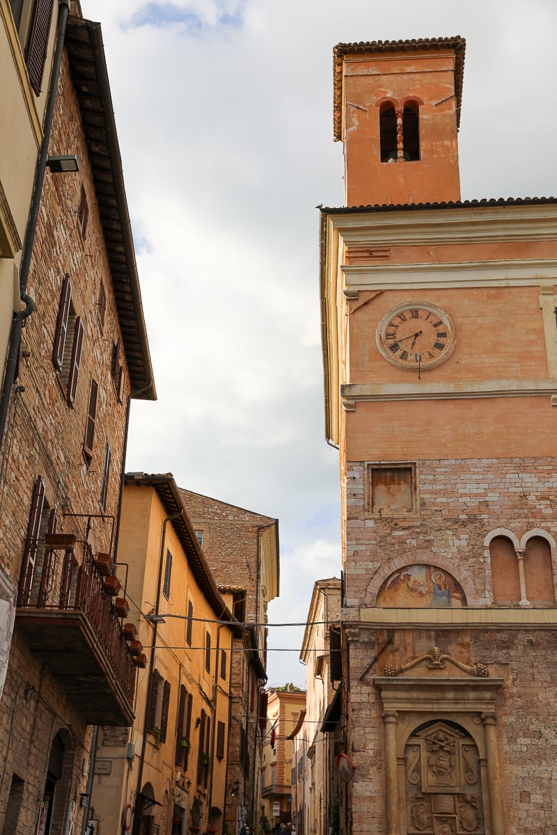 Stone buildings with brick walls and a clock tower in Spello, Umbria