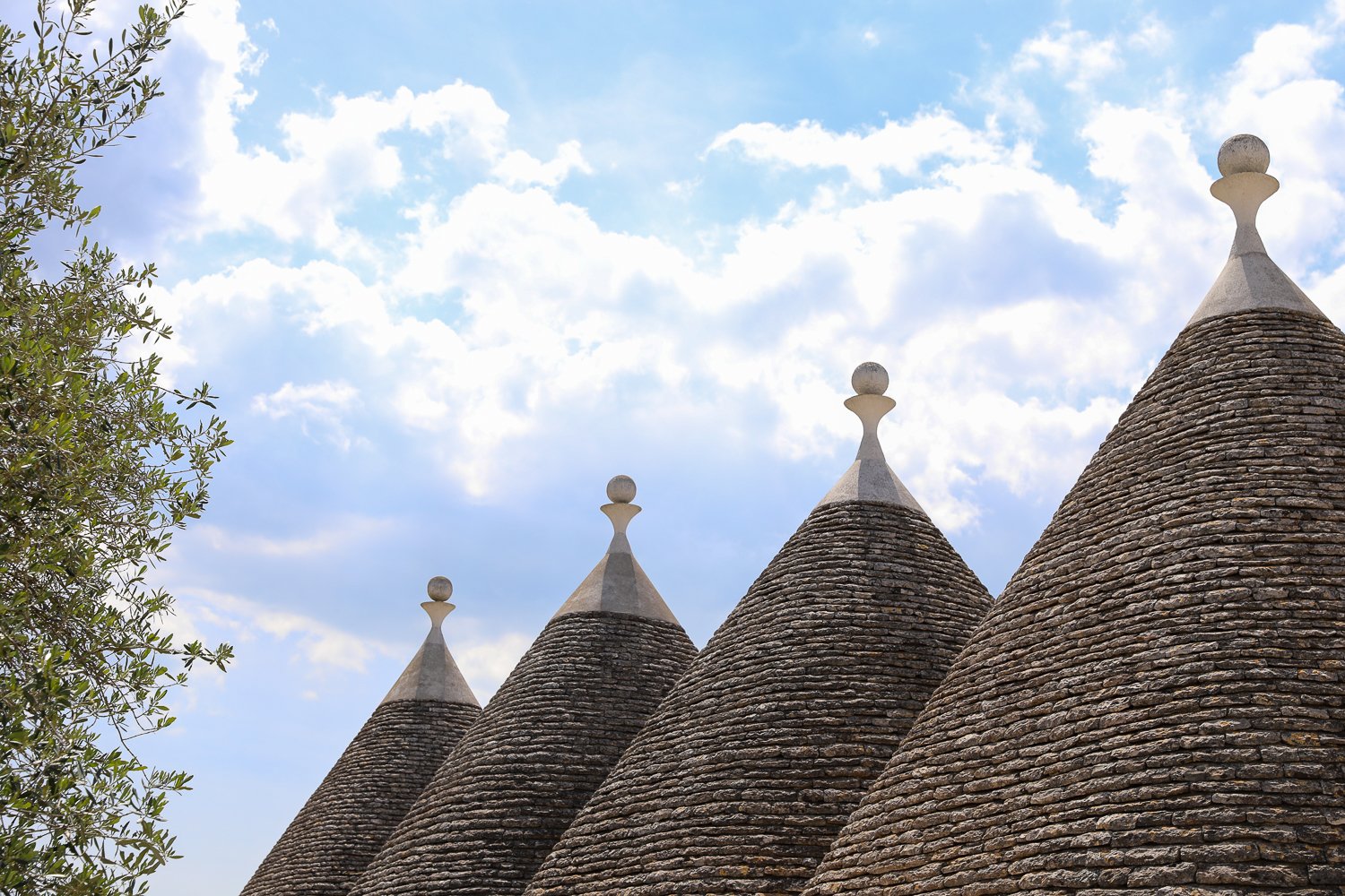Trulli rooftops against the partly cloudy blue skies of Italy