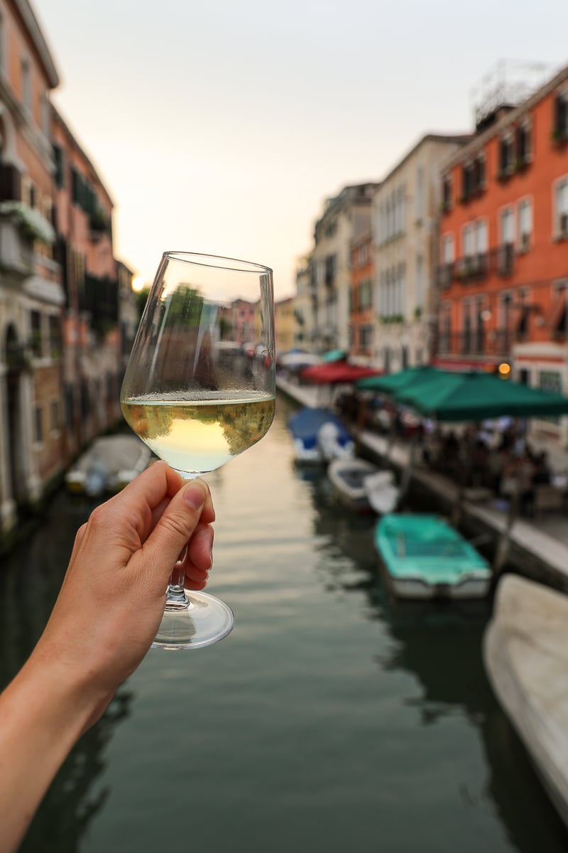 Maddy holding a glass of wine with a Venice canal in the background