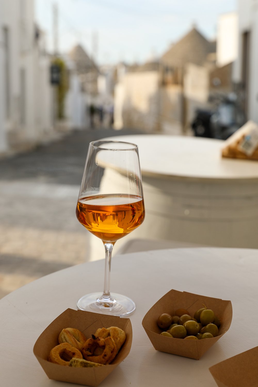 Pugliese food and olives served with wine on a glass. Eating traditional Pugliese food is one of the things to do in Alberobello.