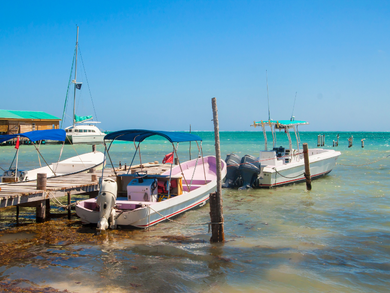 Boats docked on a small pier on a sunny day in Caye Caulker