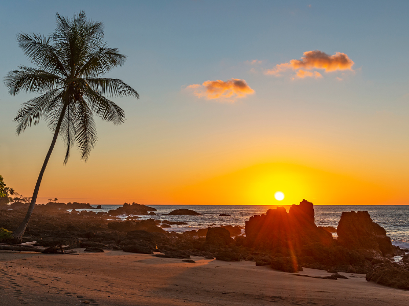 Orange sunset by a rocky shore at Corcovado National Park