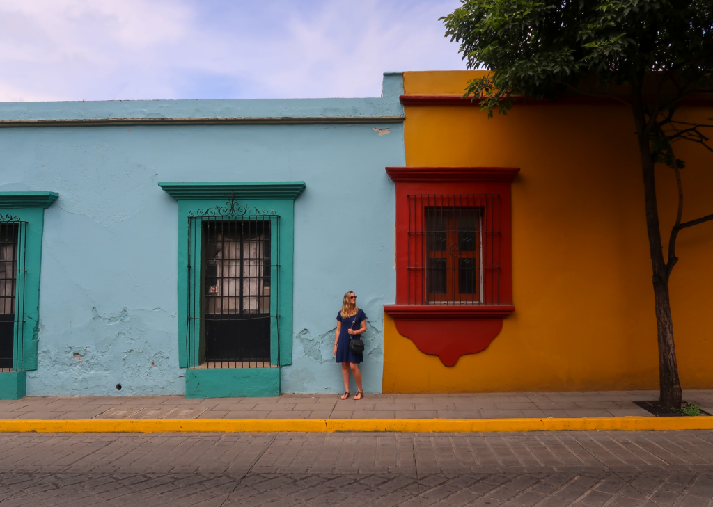 Maddy standing in front of some colorful colonial buildings in Oaxaca City