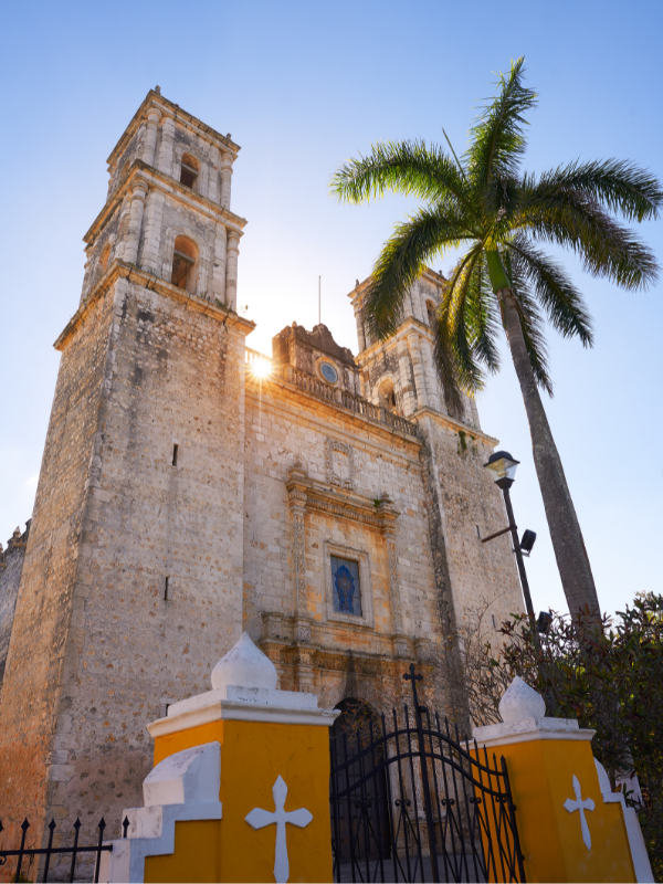 The San Servacio Church and a palm tree on a sunny day in Valladolid. Visiting this church is one of the best things to do in Valladolid, Mexico!