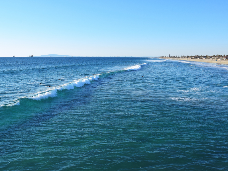 surfers riding waves in Huntington Beach, California, AKA Surf City. Learning to surf is a must on your California bucket list!