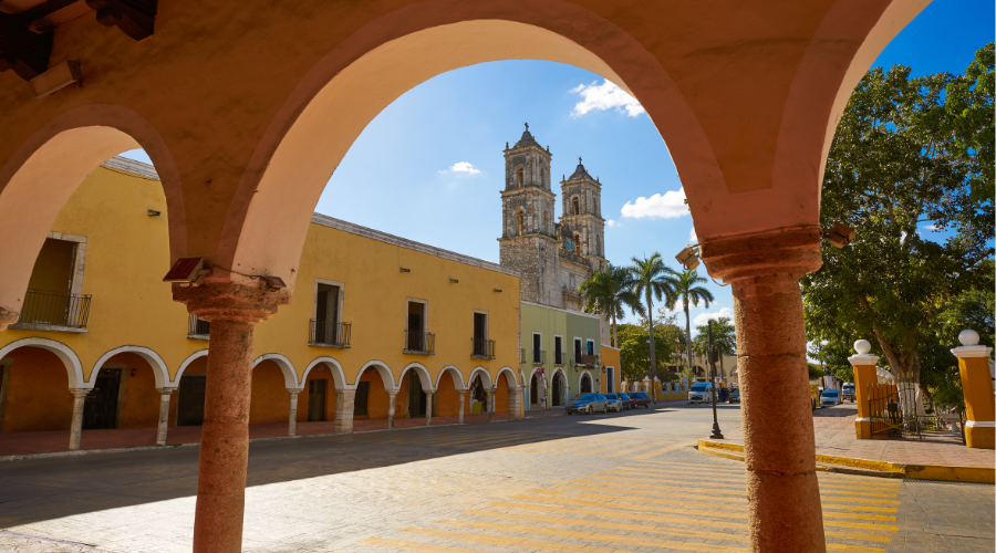 The colorful central plaza of Valladolid, seen through an arched hallway.